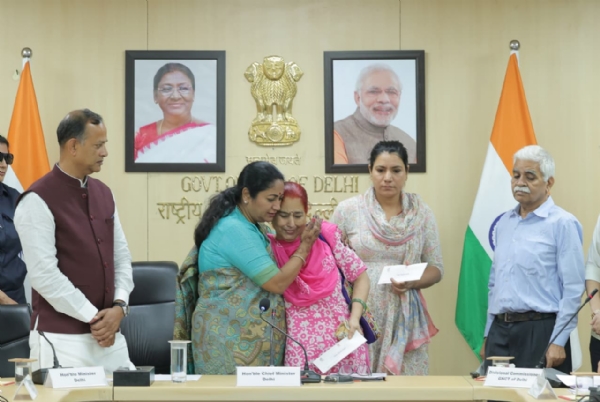 दिल्ली सचिवालय में कोविड में ड्यूटी पर जान गंवाने वाले सरकारी कर्मियों के परिजनों एक करोड़ रुपये का चेक देते मुख्यमंत्री रेखा गुप्ता