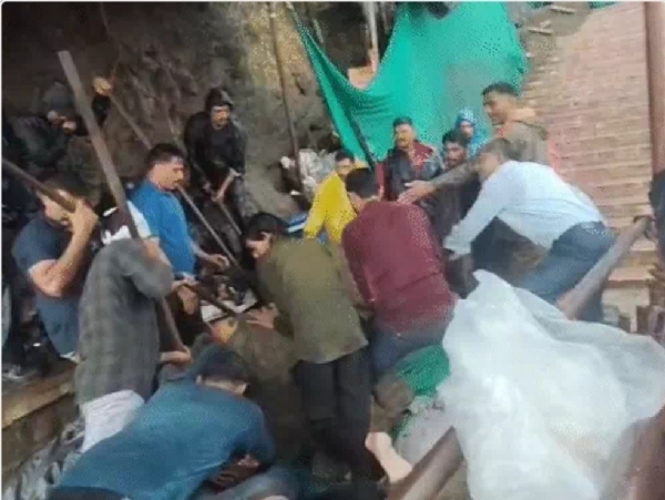 अचानक चट्टानें और मलबा गिरने से कई श्रद्धालु चपेट में आने के बाद बचाव कार्य करते सरकारी कर्मी